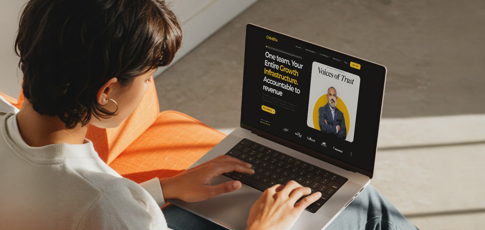 An over-the-shoulder view of a person typing on a laptop that displays The Chimera Marketing website homepage, featuring the headline "One team. Your Entire Growth Infrastructure. Accountable to revenue" alongside a "Voices of Trust" client testimonial card.