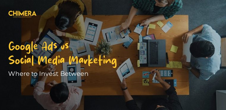 An overhead view of a creative team collaborating at a wooden table covered in UI/UX wireframes and digital sketches, featuring the Chimera Marketing logo and text overlay "Google Ads vs Social Media Marketing: Where to Invest Between.